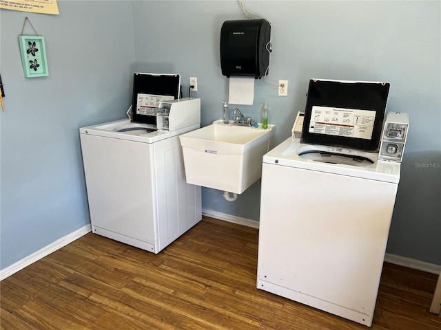 washroom with baseboards, washer and dryer, wood finished floors, and a sink