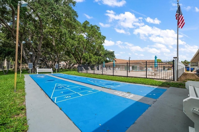 surrounding community with shuffleboard, fence, and a lawn