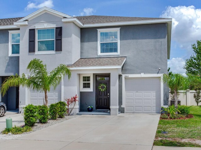 traditional-style house with an attached garage, concrete driveway, and stucco siding