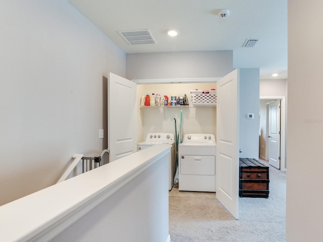 washroom with light carpet, visible vents, washer and clothes dryer, and laundry area