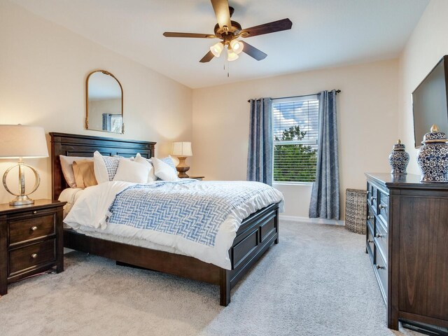 bedroom featuring ceiling fan, light carpet, and baseboards