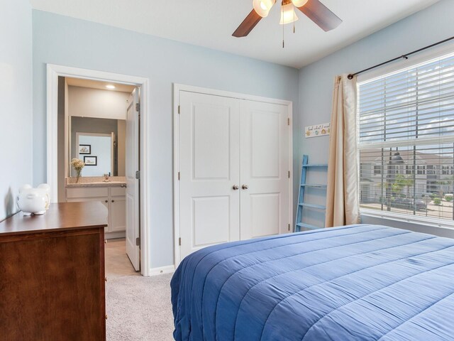 bedroom featuring connected bathroom, a closet, baseboards, light colored carpet, and ceiling fan
