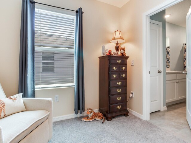 sitting room with baseboards and light carpet