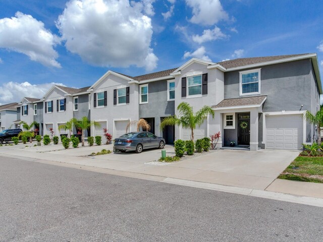 townhome / multi-family property with stucco siding, an attached garage, a residential view, and concrete driveway