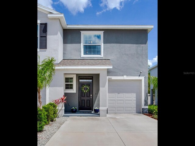 exterior space with an attached garage, concrete driveway, and stucco siding