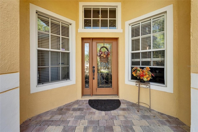 property entrance with stucco siding and a porch