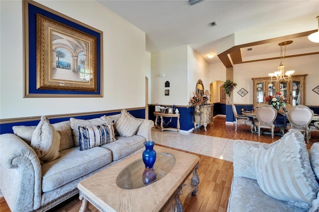 living room with arched walkways, a chandelier, wood finished floors, and a tray ceiling