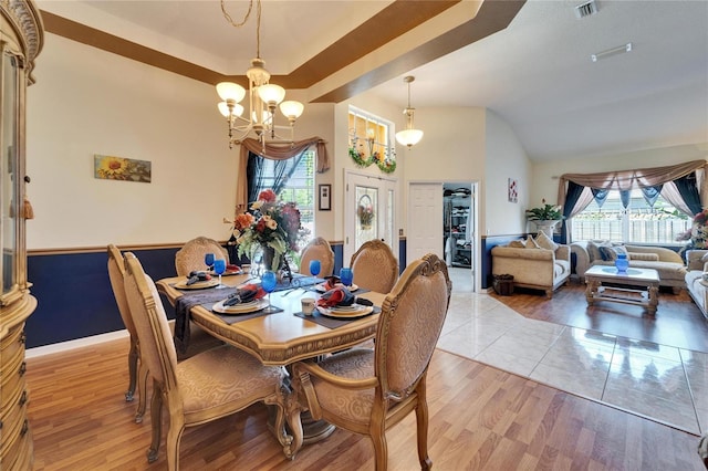 dining space with a chandelier, healthy amount of natural light, light wood finished floors, and lofted ceiling
