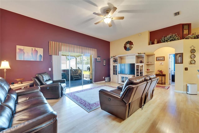 living area with a ceiling fan, arched walkways, light wood-type flooring, and baseboards