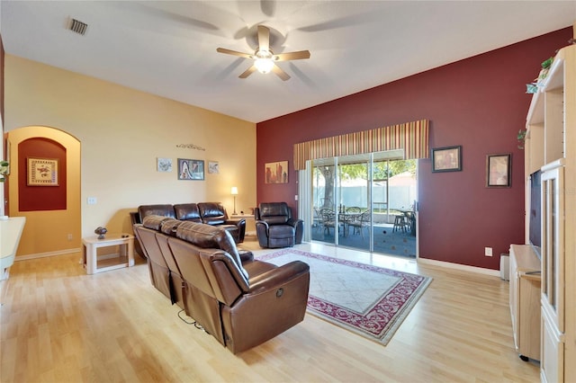 living area featuring a ceiling fan, light wood-type flooring, arched walkways, and baseboards