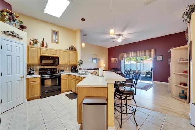 kitchen featuring black appliances, light brown cabinetry, a peninsula, light countertops, and light tile patterned flooring