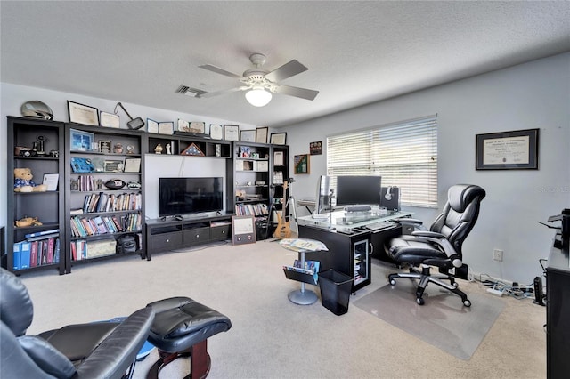 office space featuring carpet flooring, a ceiling fan, and a textured ceiling