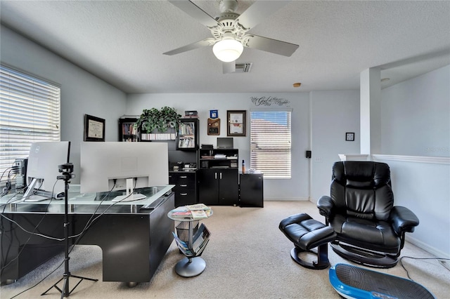 office space featuring light colored carpet, a ceiling fan, baseboards, and a textured ceiling