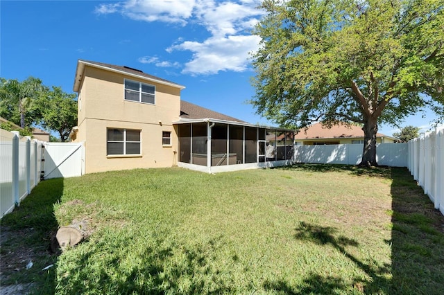 rear view of house featuring a sunroom, stucco siding, and a gate