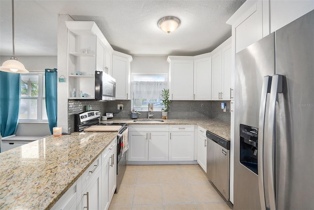 831 72nd Ave N, Saint Petersburg, FL 33702 - kitchen with light tile patterned floors, white cabinets, a sink, stainless steel appliances, and decorative backsplash