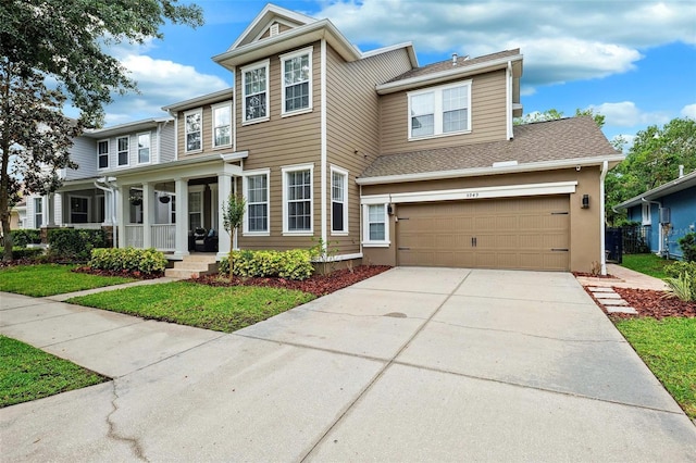 traditional home with a porch, concrete driveway, and a garage