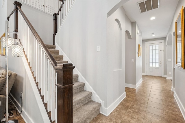 foyer with baseboards, recessed lighting, stairs, visible vents, and arched walkways