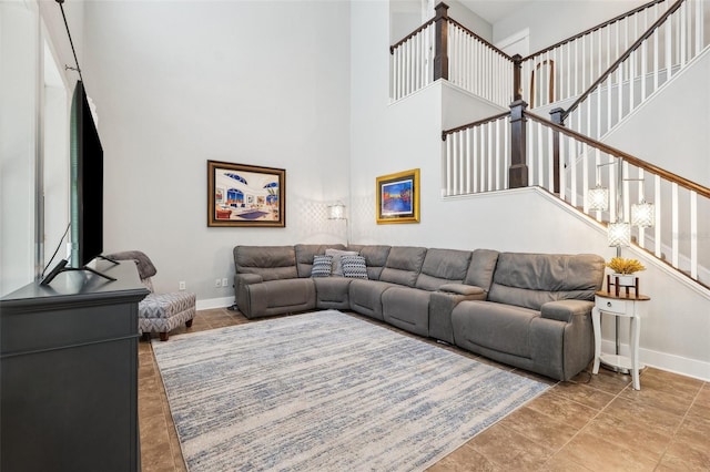 living area with a high ceiling, baseboards, and stairway