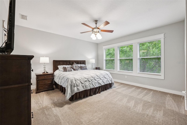 bedroom featuring visible vents, light colored carpet, baseboards, and a ceiling fan