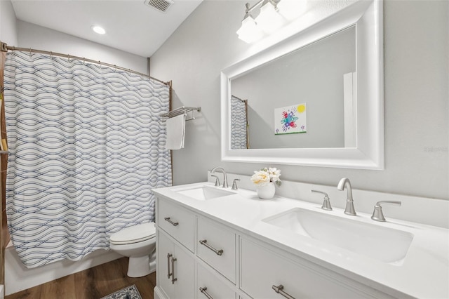 bathroom with toilet, wood finished floors, a sink, and visible vents