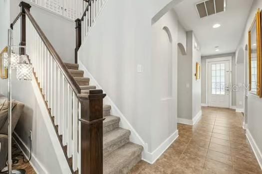 entryway with baseboards, recessed lighting, tile patterned flooring, visible vents, and arched walkways