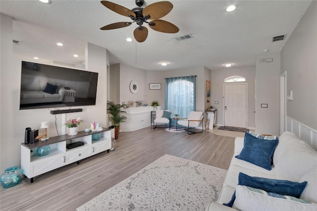 living area featuring a textured ceiling, visible vents, and wood finished floors