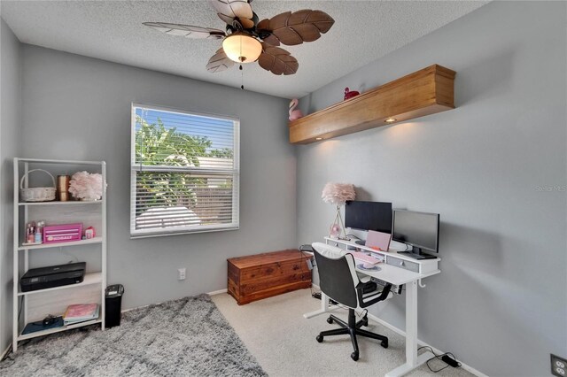 carpeted home office with a textured ceiling, baseboards, and a ceiling fan