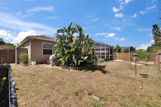 view of yard with a fenced backyard and glass enclosure