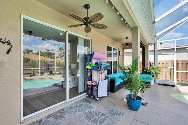 view of patio featuring fence, an outdoor pool, ceiling fan, and glass enclosure