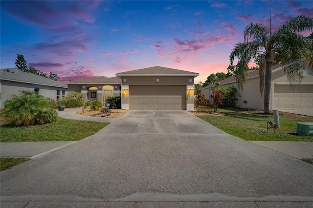 ranch-style home with an attached garage, driveway, a yard, stucco siding, and central AC unit