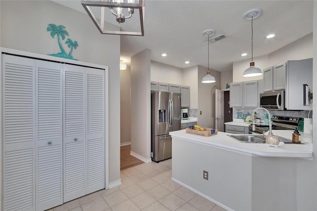 4017 3rd Ave E, Bradenton, FL 34208 - kitchen featuring appliances with stainless steel finishes, a peninsula, light countertops, gray cabinetry, and tasteful backsplash