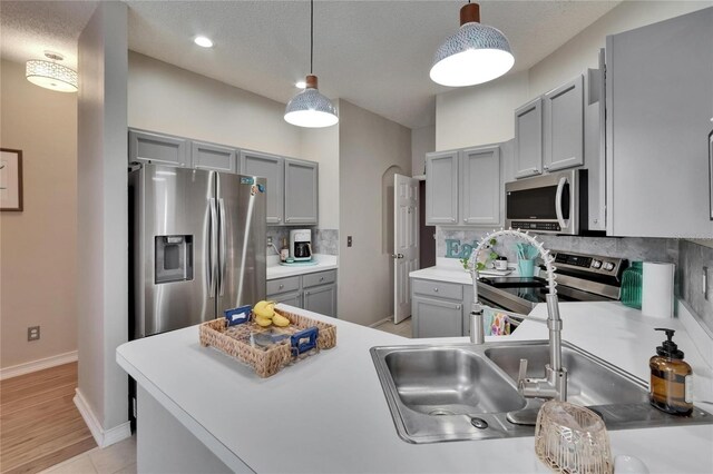 4017 3rd Ave E, Bradenton, FL 34208 - kitchen featuring stainless steel appliances, gray cabinets, decorative backsplash, decorative light fixtures, and light countertops