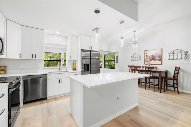 1047 Deer Hollow Way, Sarasota, FL 34232 - kitchen featuring stainless steel appliances, light countertops, a sink, light wood-type flooring, and a chandelier