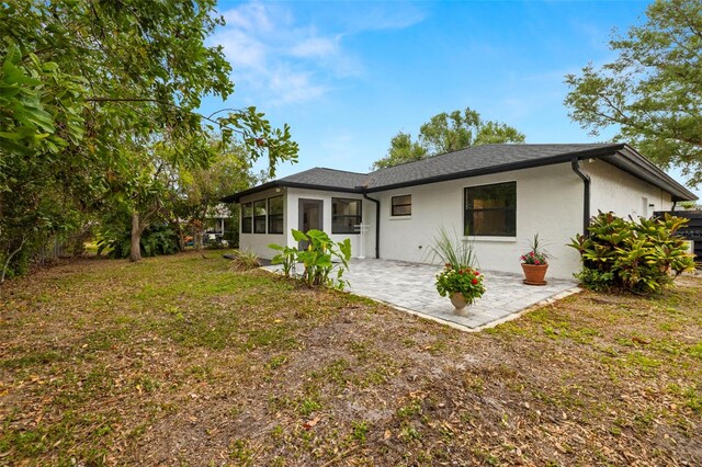 1047 Deer Hollow Way, Sarasota, FL 34232 - rear view of house with a patio area, a shingled roof, a sunroom, and stucco siding