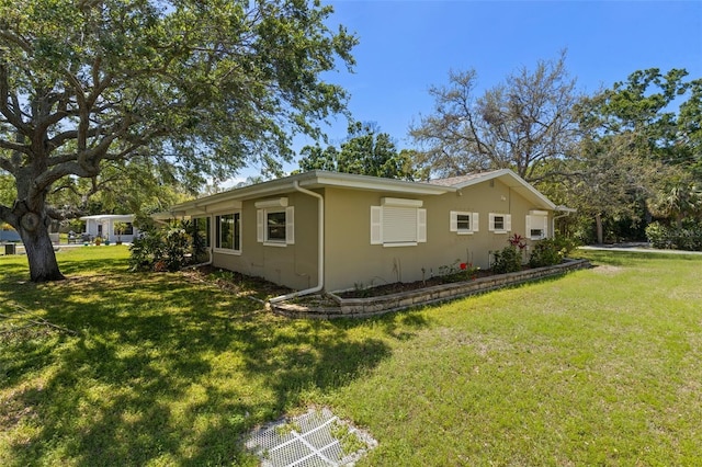 view of side of home with a yard and stucco siding