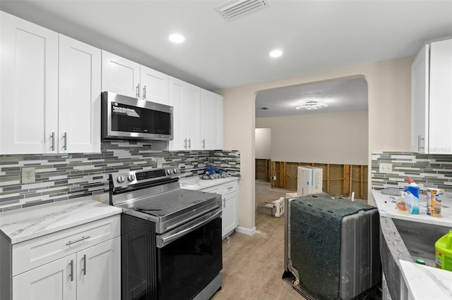 kitchen with backsplash, white cabinets, light stone countertops, visible vents, and appliances with stainless steel finishes