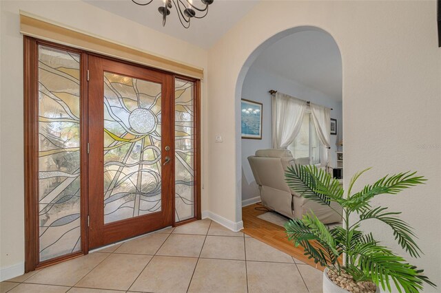 4490 38th Way S, Saint Petersburg, FL 33711 - entrance foyer with arched walkways, light tile patterned floors, baseboards, and an inviting chandelier