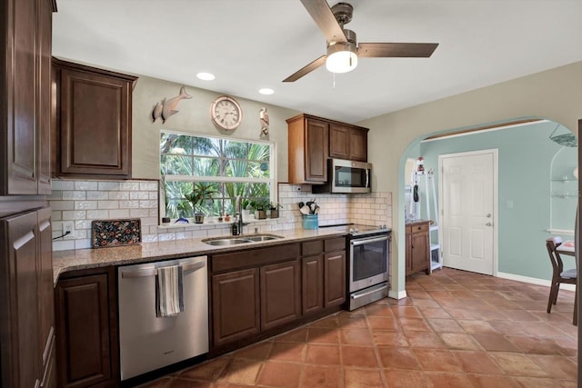 2049 Broadway, Clearwater, FL 33755 - kitchen featuring stainless steel appliances, a sink, arched walkways, decorative backsplash, and light stone counters