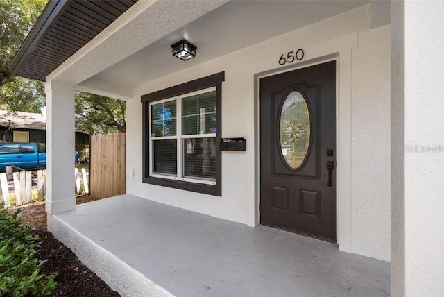 property entrance featuring a porch and stucco siding