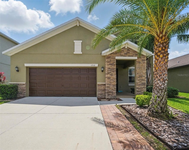 view of front of property with driveway, stucco siding, stone siding, and an attached garage