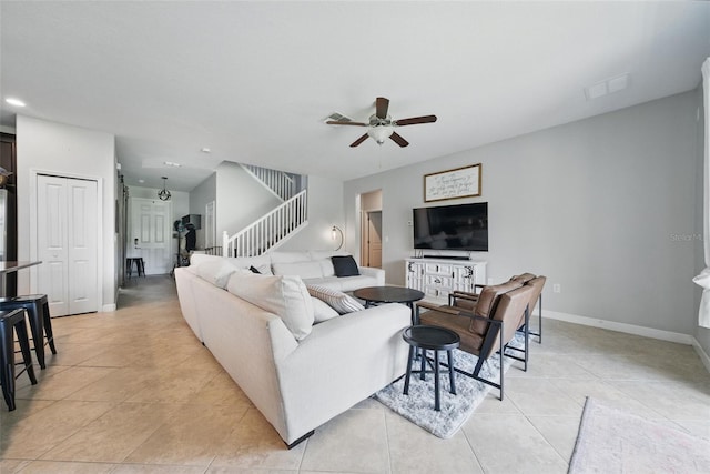 living room with ceiling fan, visible vents, stairway, light tile patterned flooring, and baseboards