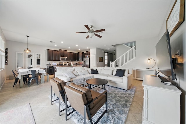 living room with light tile patterned floors, baseboards, visible vents, ceiling fan, and stairs