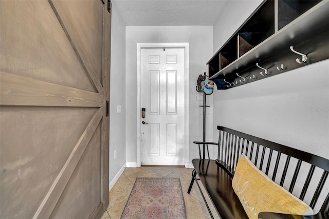entryway featuring tile patterned floors, a barn door, baseboards, and a textured ceiling
