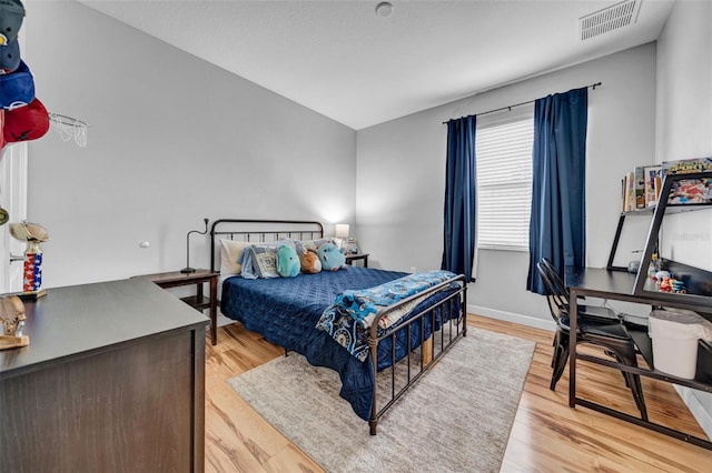 bedroom featuring visible vents, light wood-style flooring, and baseboards