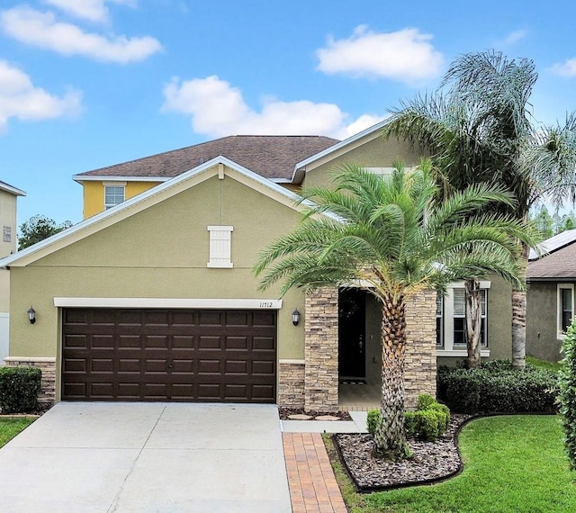 mediterranean / spanish home with concrete driveway, stone siding, a garage, and stucco siding