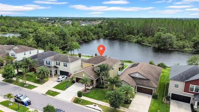 bird's eye view featuring a wooded view, a residential view, and a water view