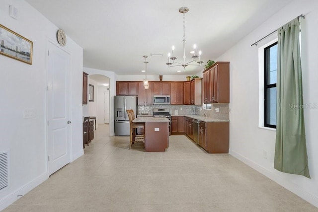 1214 Florablu Dr, Seffner, FL 33584 - kitchen featuring arched walkways, stainless steel appliances, a chandelier, a center island, and decorative backsplash