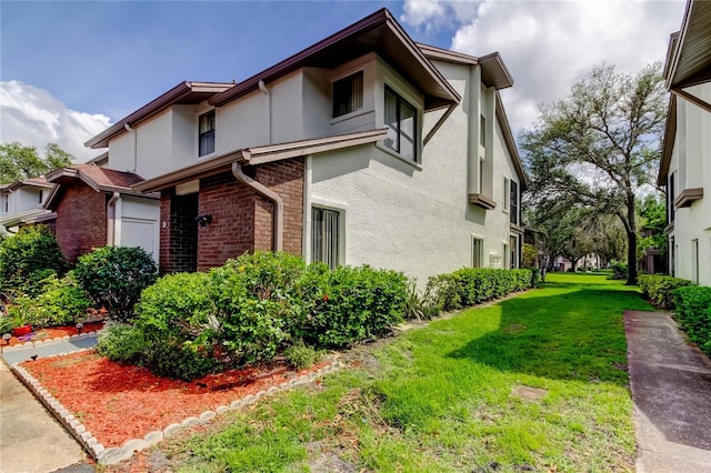612 Fairmont Ave Unit D, Safety Harbor, FL 34695 - view of property exterior featuring brick siding, a lawn, and stucco siding