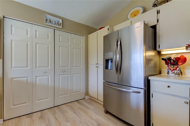 612 Fairmont Ave Unit D, Safety Harbor, FL 34695 - kitchen with stainless steel fridge, a textured ceiling, light countertops, white cabinetry, and light wood finished floors