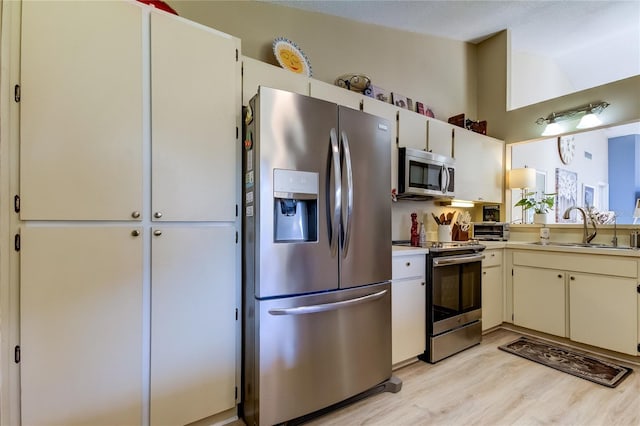 612 Fairmont Ave Unit D, Safety Harbor, FL 34695 - kitchen featuring a sink, light countertops, appliances with stainless steel finishes, light wood-style floors, and lofted ceiling